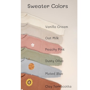 K&ouml;nnte beinhalten: Sechs Pullover in verschiedenen Farben mit gestickten Designs. Die Farben sind Vanillecreme, Hafermilch, Pfirsichrosa, staubiges Oliv, ged&auml;mpftes Blau und Terrakotta.