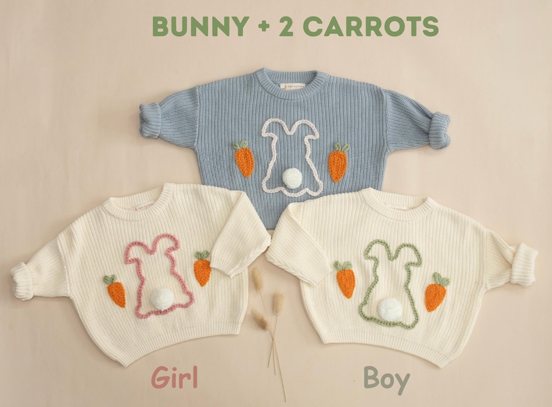K&ouml;nnte beinhalten: Zwei wei&szlig;e Strickpullover mit gestickten Hasen- und Karottenmotiven. Ein Pullover hat einen rosa Hasen und der andere einen gr&uuml;nen Hasen. Der Text "Bunny + 2 Carrots" befindet sich oben im Bild. Der Text "Girl" befindet sich unter dem Pullover mit dem rosa Hasen und der Text "Boy" befindet sich unter dem Pullover mit dem gr&uuml;nen Hasen.