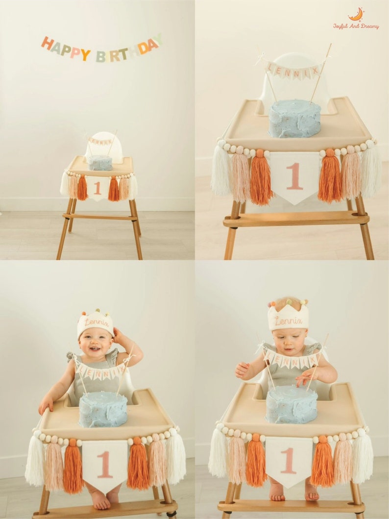 May include: A baby girl sits in a high chair with a blue and white cake in front of her. The high chair is decorated with a white, peach, and orange tassel garland and a banner that says "Lennia". The cake has a number one candle on top. The background is a white wall with a banner that says "Happy Birthday".