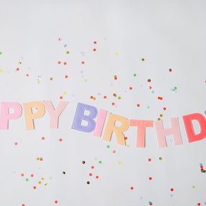 May include: A colorful felt banner that says "Happy Birthday" with confetti scattered around it.