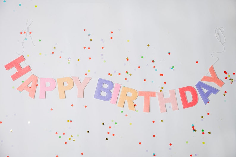 May include: A colorful felt banner that says "Happy Birthday" with confetti scattered around it.