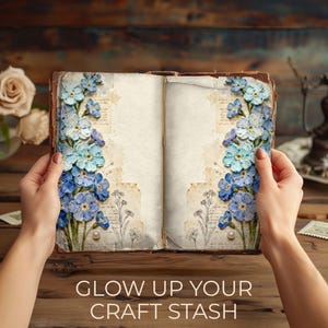 Flatlay scene of an open journal displaying white floral Whispered Blooms pages with pearl accents and handwritten paper textures. Surrounding props include a wax seal, candle, tea, and fountain pen, creating a calm, vintage-inspired writing atmosphere. A green banner reads “Whispered Blooms – Print. Cut. Create.”