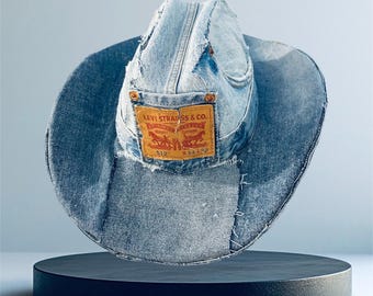May include: A blue denim cowboy hat with a Levi Strauss & Co. patch. The hat is made from repurposed denim and has a distressed look.