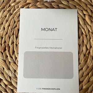 K&ouml;nnte beinhalten: Eine wei&szlig;e Karte mit dem Wort "MONAT" in schwarzer Schrift oben. Unter dem Wort "MONAT" befindet sich eine Linie und der Text "Finanzielle Monatsziel" in schwarzer Schrift. Unter dem Text befindet sich ein graues Rechteck. Der Text "&copy; DIE FINANZKOMPLIZIN" ist in schwarzer Schrift unten auf der Karte.