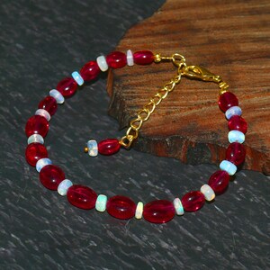Pode incluir: Um bracelete de pedras preciosas vermelhas e brancas com um fecho dourado. O bracelete é feito de pedras preciosas vermelhas de forma oval e pedras preciosas brancas redondas.