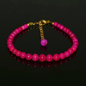May include: A pink opal beaded bracelet with a gold clasp and a small pink opal charm.