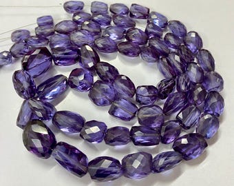 May include: A strand of faceted, oval-shaped amethyst beads. The beads are a deep purple color and have a sparkling, polished finish. The beads are strung on a thin, clear cord, and are suitable for jewelry making.