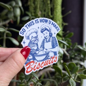 Puede incluir: Una pegatina azul y blanca con un gato de dibujos animados y una mujer con un gorro de cocinero. El texto de la pegatina dice "So this is how u make biscuits".