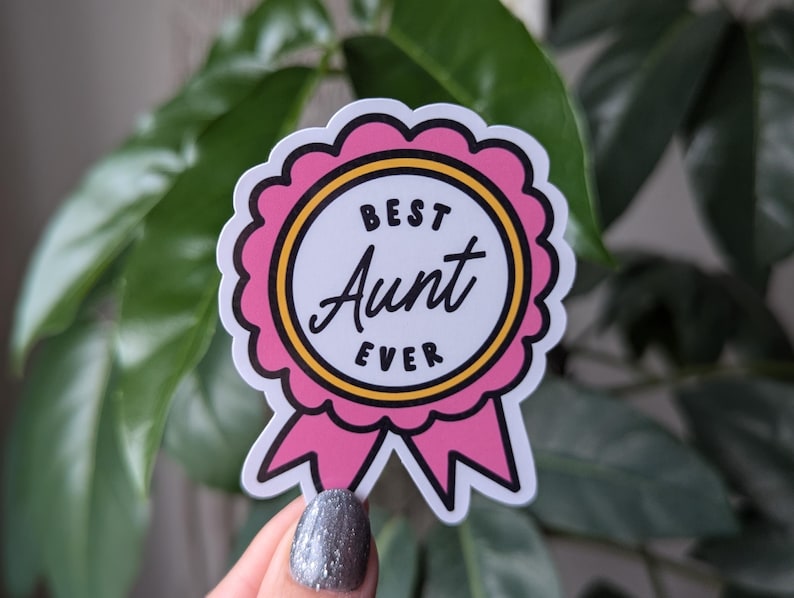 May include: Pink and yellow sticker with a ribbon and the text "Best Aunt Ever".