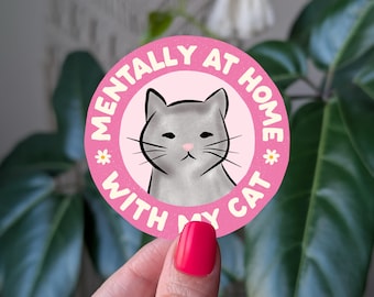 May include: Pink and white round sticker with the text "Mentally at home with my cat" and a cartoon grey cat with a grumpy expression.