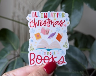 May include: White sticker with colorful illustrations of books and snowflakes. The text reads "All I want for Christmas is more books".
