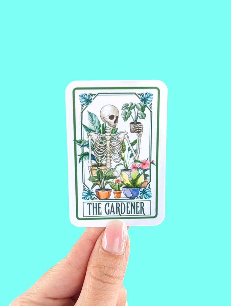 Puede incluir: Una pegatina blanca con un borde verde muestra un esqueleto sosteniendo una planta en maceta. El esqueleto est&aacute; rodeado de otras plantas en maceta. El texto "THE GARDENER" est&aacute; impreso en verde en la parte inferior de la pegatina.