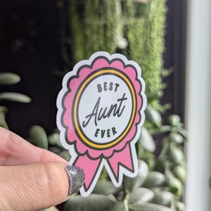 May include: Pink and yellow sticker with a ribbon. The sticker says "Best Aunt Ever".