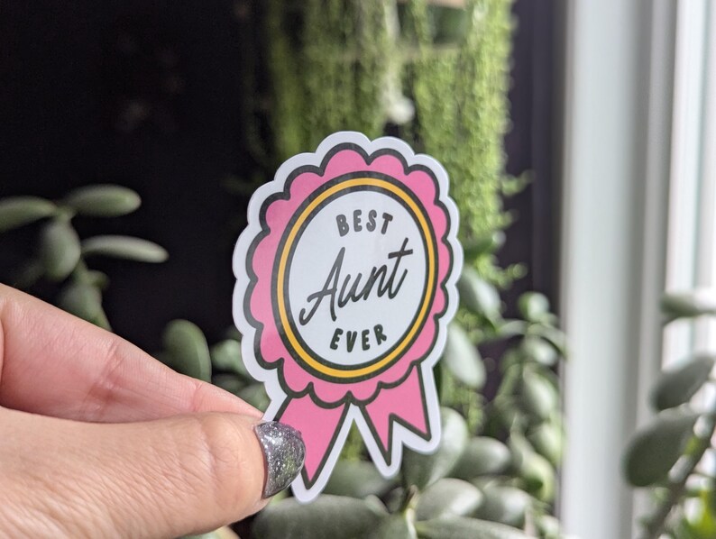 May include: Pink and yellow sticker with a ribbon. The sticker says "Best Aunt Ever".