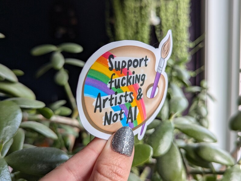 Może przedstawiać: Biała naklejka z tęczą i paletą farb. Naklejka głosi "Support fucking Artists & Not AI!"