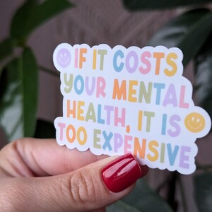 May include: A colorful sticker with the text "If it costs your mental health, it is too expensive." The sticker has a smiley face on each side.
