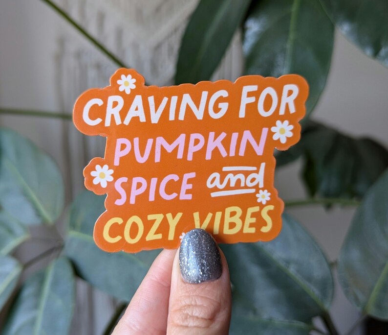 May include: Orange sticker with white daisy accents and the text "CRAVING FOR PUMPKIN SPICE and COZY VIBES".