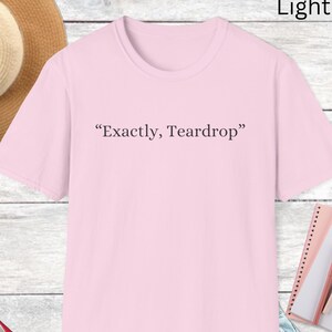 May include: Light pink t-shirt with the text "Exactly, Teardrop" printed on the front.