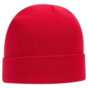 Op de afbeelding: Een effen rode beanie-muts met een omgeslagen rand. De muts is gemaakt van geribbelde gebreide stof. De beanie is een winteraccessoire, geschikt voor koud weer.