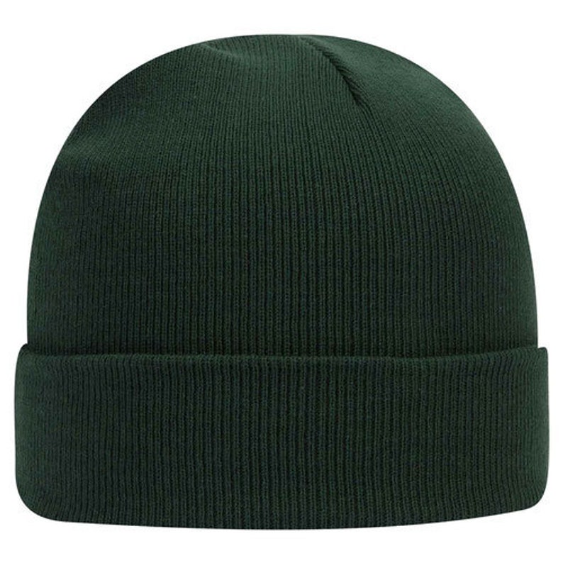 Op de afbeelding: Donkergroene gebreide muts met een omgeslagen rand. De hoed is gemaakt van een geribbelde gebreide stof. Deze wintermuts is een veelzijdig accessoire voor koud weer.