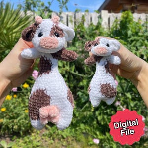 Könnte beinhalten: Zwei handgefertigte gehäkelte Kuh-Plüschtiere. Die Kühe sind weiß mit braunen Flecken und Akzenten, einschließlich Ohren, Hufen und einem Euter. Die Plüschtiere haben schwarze Augen und rosafarbene Nasen. Die größere Kuh ist etwa 25 cm groß.