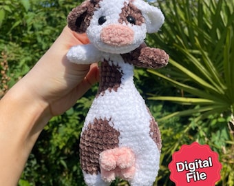 May include: A handmade crochet cow plushie in white, brown, and pink. The cow has a soft, textured appearance with brown spots, ears, and a pink muzzle and udder. The image includes a red sticker that says "Digital File".