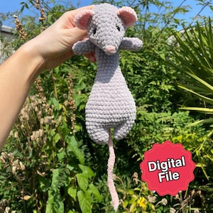 Könnte beinhalten: Ein handgefertigtes, graues Häkelmaus-Spielzeug mit rosa Ohren, Nase und Schwanz. Die Maus hat kleine schwarze Augen und ausgestreckte Arme. Das Bild enthält einen roten Aufkleber mit der Aufschrift "Digital File".