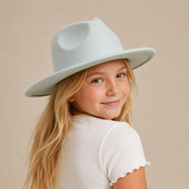 May include: A light blue fedora hat with a structured crown and a wide, flat brim. The hat features a smooth, felt-like texture and a matching tonal band around the base of the crown, providing a clean and uniform appearance for this headwear.