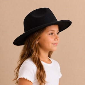 May include: A solid black fedora hat with a structured crown and a wide, flat brim. The hat features a smooth, matte finish and a simple design, showcasing a classic silhouette that sits level on the head with a clean, uniform appearance.
