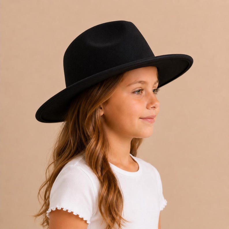 May include: A solid black fedora hat with a structured crown and a wide, flat brim. The hat features a smooth, matte finish and a simple design, showcasing a classic silhouette that sits level on the head with a clean, uniform appearance.