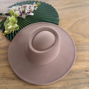 May include: A light brown fedora hat with a wide brim and a tall, rounded crown.