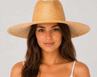 May include: A light tan straw fedora hat with a wide brim and a pinched crown. The hat features a woven texture throughout, creating a structured shape with a flat, circular brim that extends outward from the base of the crown.