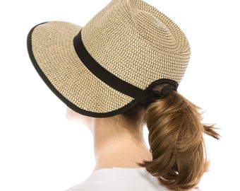 May include: A beige straw hat with a black band and trim. The hat has a curved brim and a ponytail opening at the back. The hat is designed to be worn with the hair pulled through the opening.