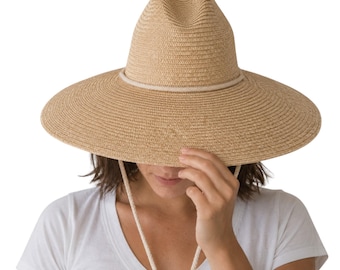 May include: A tan straw hat with a wide brim and a pinched crown. The hat features a light-colored rope band around the base of the crown and a matching rope chin strap with a dark brown bead toggle, providing a secure fit for outdoor wear.