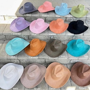 Könnte beinhalten: Eine Auswahl an Cowboyhüten in verschiedenen Farben, darunter Grau, Pfirsich, Blau, Salbei, Lavendel, Rosa, Orange, Schwarz, Mint, Karamell, Olive, Türkis, Elfenbein, Taupe, Kamel und Braun. Die Hüte sind auf Steinstufen angeordnet.