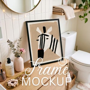 May include: A black rectangular frame containing an abstract illustration of a zebra head with bold black stripes on a beige background. The artwork features a white zebra face with a black muzzle and ears, displayed in a modern bathroom setting.