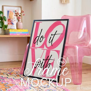 May include: A black rectangular picture frame containing a white poster with large, bold, hot pink brushstroke lettering that spells out the word LOVE. Overlaid on the pink letters is the black cursive text that reads do it with.