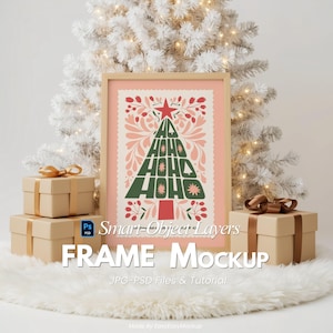 May include: A framed Christmas-themed art print with a festive design. The artwork features a green Christmas tree shape with the words "HO HO HO" and red and pink floral accents. The frame is light brown, and the image is set against a white background with gift boxes.