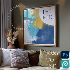 May include: A framed abstract painting with blue, yellow, and white paint splatters. The frame is a light brown wood. The text "PSD FILE" is printed in white on a yellow circle in the upper right corner of the painting.