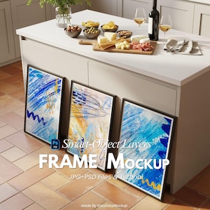 May include: Three framed abstract art prints with black frames, leaning against a white cabinet. The art features blue, yellow, and white brushstrokes. A kitchen counter displays snacks, wine, and glasses.
