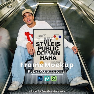 May include: A framed poster with the text "MY STYLE IS PUBLIC DOMAIN HAHA" in black and white. The poster is held by a person wearing a white sweater with red accents, blue jeans, and a tan cap. The image includes the text "Frame Mockup" and "PSD/JPG & Tutorial".