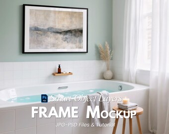 May include: A bathroom scene featuring a framed landscape art print with a black frame. The room includes a white bathtub, a wooden stool, and a window with white curtains. The text "FRAME MOCKUP" is visible.