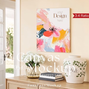 Puede incluir: Una maqueta de lienzo con un diseño floral en rosa, naranja, amarillo y verde azulado. El lienzo es rectangular y tiene el texto "your Design here". Un jarrón con la palabra "HOME" y un ramo de flores blancas están sobre una superficie de madera.