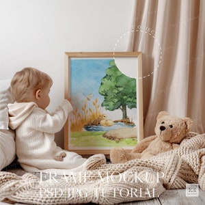 Puede incluir: Una pintura acuarela enmarcada de un pato en un estanque con un &aacute;rbol y una lib&eacute;lula. La pintura est&aacute; en un suelo de madera con una manta beige y un oso de peluche.