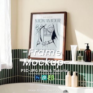 May include: A framed art print with the text "MON AMOUR" in a bathroom setting. The artwork features a black and white illustration. The scene includes a white shelf with toiletries and a green tiled wall.