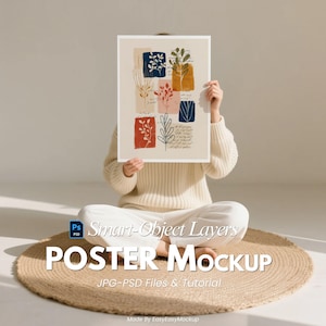 Könnte beinhalten: Ein Poster-Mockup mit einem botanischen Design in roten, blauen und orangefarbenen Quadraten. Das Poster wird von einer Person gehalten, die auf einer runden, gewebten Matte sitzt. Der Text "POSTER Mockup" ist sichtbar.