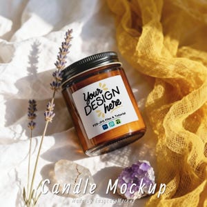 May include: A candle in a clear glass jar with a black lid. The label reads "Your DESIGN here". The candle is surrounded by lavender sprigs, crystals, and a yellow cloth. The words "Candle Mockup" are at the bottom.