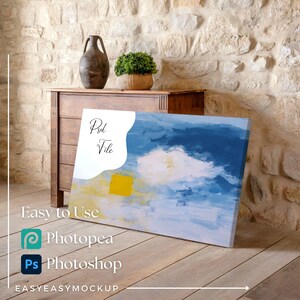 May include: An abstract art canvas with blue, yellow, and white brushstrokes, leaning against a wooden surface. The canvas has the text "Psd File" and the words "Easy to Use" with the logos for Photopea and Photoshop.