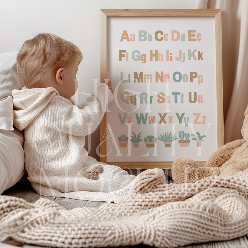 Puede incluir: Un cuadro enmarcado con el alfabeto con letras de colores e ilustraciones de plantas en macetas. El cuadro est&aacute; colgado en una pared y un ni&ntilde;o peque&ntilde;o est&aacute; alcanzando hacia &eacute;l.