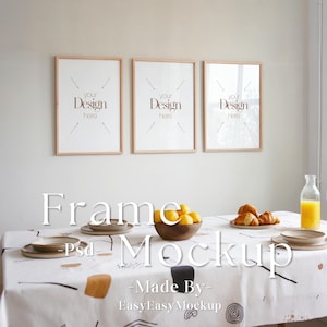 May include: Three wooden picture frames with white mats and the text "your Design here" in each frame. The frames are hanging on a white wall above a table with a white tablecloth with a black and brown abstract pattern. There are lemons in a wooden bowl and croissants on a plate on the table.